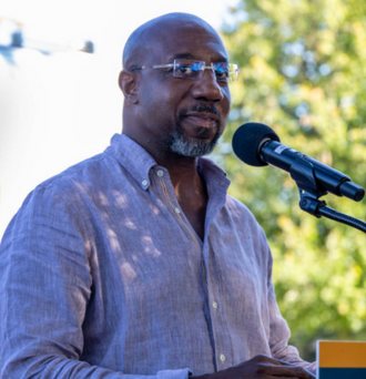 Raphael Warnock speaks into a microphone 